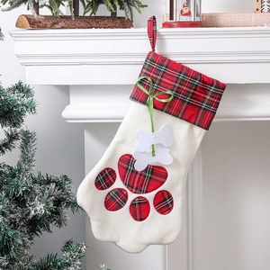 Détail d'une chaussette de Noël en patte de chien avec motif à carreaux sur cheminée blanche