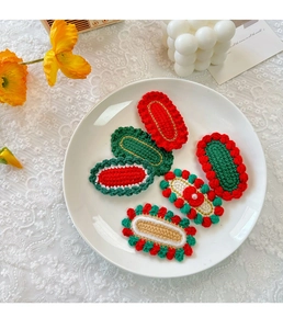 Detailed view of six handmade crochet Christmas hair clips on a white ceramic plate