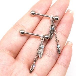 Detail of silver steel barbell nipple rings with feather charms and blue crystals