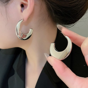 Macro shot of polished silver chunky C-shaped hoop earrings with a glossy metal finish