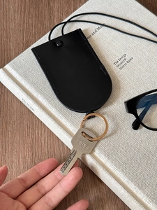 Detail of black leather magnetic glasses holder with golden keychain on a book