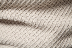 Detailed close-up of light beige men's sweater with premium waffle knit cotton texture