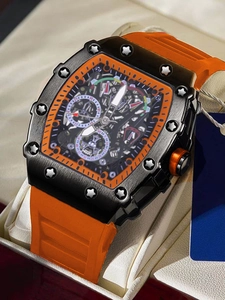 Detalle de reloj automático con forma de tonel con correa naranja y caja negra en cojín