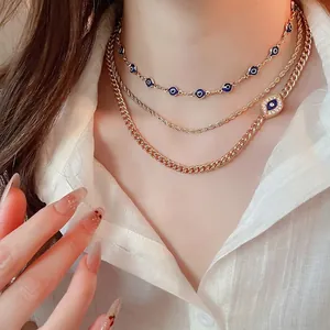 Three-layer gold evil eye necklace set with zircon pendants on model in white shirt