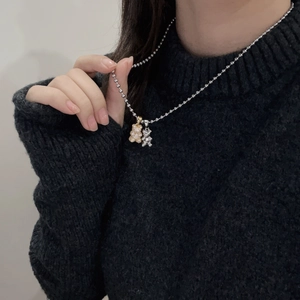 Detailed close-up of a silver beaded chain necklace with two micro-set zircon bear pendants