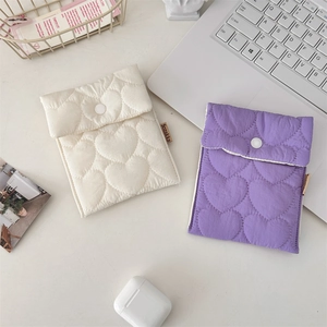 Detailed view of quilted heart pattern small storage pouches in beige and purple