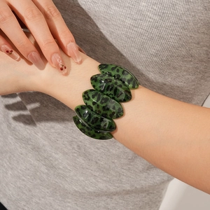 Close-up of deep green leopard print resin bangle showing glossy finish and black spots