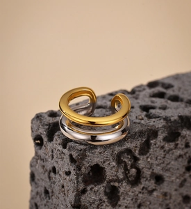Macro view of double-layered silver and gold ear cuff on a textured rock surface