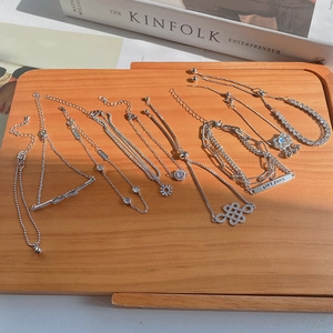 Silver vintage pearl and charm bracelets featuring Good Luck tags on a wooden tray