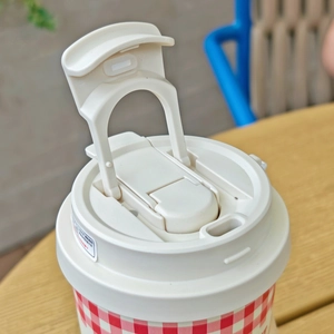 Close-up of the ivory flip-top lid with PP safety material markings on a checkered cup