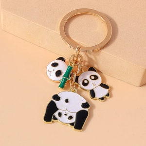 Detail of golden panda keychain featuring black and white charms and a green bamboo leaf