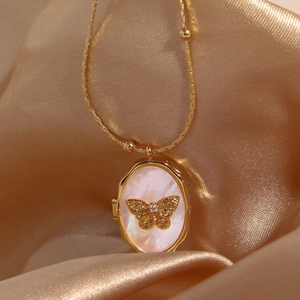 Goldene Medaillon-Halskette mit Schmetterling aus Perlmutt auf seidigem Hintergrund