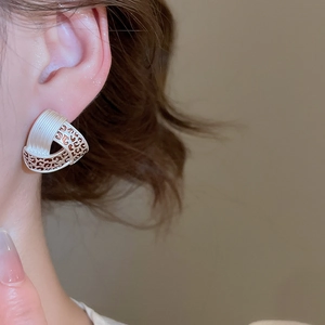 Detail of geometric silver textured earring with rose gold leopard pattern on a model