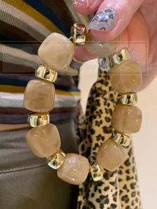 Detail of amber marble resin beads with gold metal cylinders on the hand bracelet