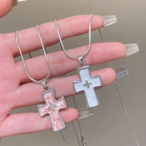 Pink and white marble cross necklaces on silver snake chains held in hand