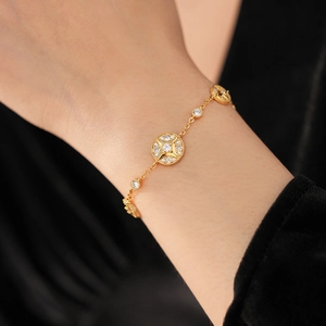 Close-up of 18K gold plated bracelet with starburst coin charm and sparkling zircons