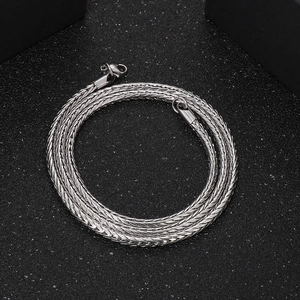 Detailed close-up of a silver braided stainless steel chain on a matte black background