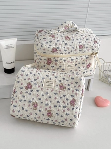 Detailed view of quilted floral bear makeup bag set on a white storage shelf
