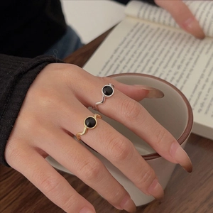 Macro detail of agate ring with wave-shaped band worn by a model in a warm cozy setting