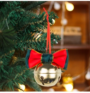 Close-up of golden bell with red and green velvet bow hanging on a Christmas tree