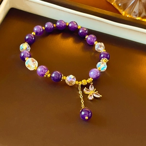 Elegant purple jade flower beaded bracelet with gold butterfly charm on brown background