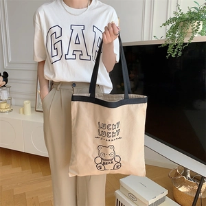 Detail of canvas tote bag showing embroidered bear motif and Lucky Lucky text print