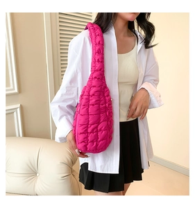 Détail du sac bandoulière rose fuchsia au design plissé souple porté sur une chemise