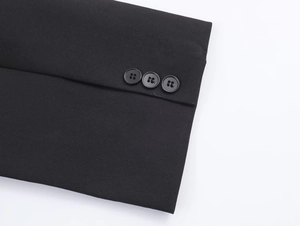 Close-up of sleeve cuffs on black blazer featuring three matching buttons and twill texture