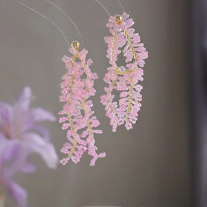 Détail de boucles d'oreilles en perles faites main avec perles roses et accents dorés élégants