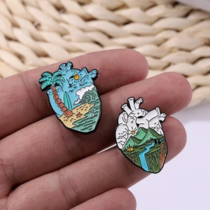Detail of anatomical heart enamel pins with beach surf and mountain forest scenes