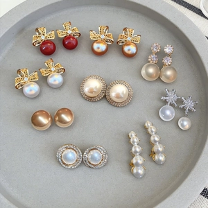 Detailed collection of pearl earrings with bow, snowflake, and gold accents in a gray tray
