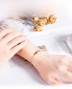 Detailed close-up of rose gold heartbeat bracelet worn on wrist with elegant accessories