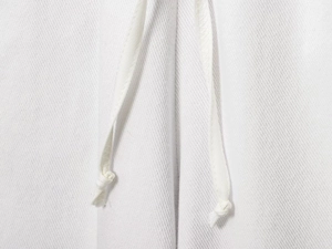 Détail du tissu en sergé blanc avec cordon de serrage ajustable et finition à nœud manuel