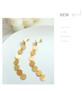 Detail of matte gold tiered circular disc earrings in a modern minimalist jewelry style