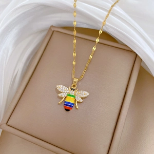 Macro shot of gold bee pendant with rainbow enamel stripes and sparkling crystal wings