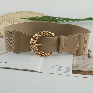 Dettaglio cintura elastica kaki con fibbia dorata intrecciata su un piano di posa elegante