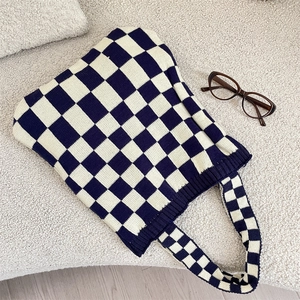 Gros plan détaillé du sac cabas tricoté à damier bleu marine et blanc sur laine