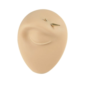 Gold stainless steel curved barbell eyebrow ring with spiked ends on a silicone model