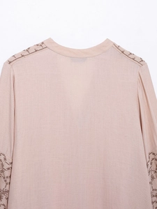 Detailed back view of pink cotton linen blouse with dark brown floral embroidery on sleeves