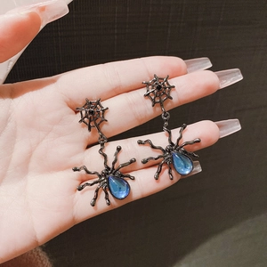 Detail of gothic spider earrings with blue teardrop stone and intricate black metal webbing