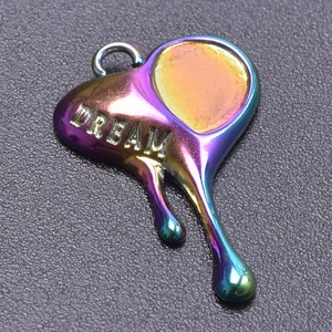 Macro shot of a melting heart pendant in rainbow finish with DREAM text engraving