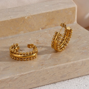 Golden chunky hoop earrings with beaded lace texture on a stone pedestal display