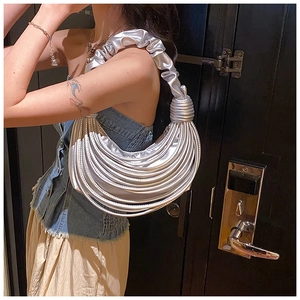 Detail shot of a silver pleated crescent handbag featuring knotted top handle design
