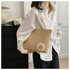 Detail of straw woven tote bag with white sunflower decoration and cotton rope handles