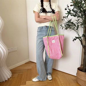 Detail of pink checkered canvas tote bag with green contrast handles in home setting