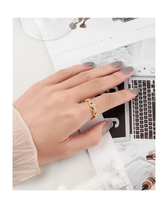 Close-up of golden chain-link ring with small transparent crystals on a model's hand