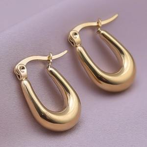 Close-up of chunky gold-plated U-shaped hoop earrings with a mirror-polished finish