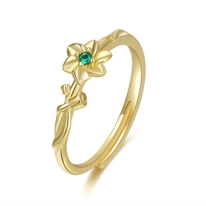 Detail of adjustable gold ring featuring flower motif and green faceted gemstone