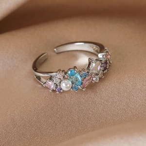 Macro detail of silver adjustable ring with colorful zircons and a white pearl on silk
