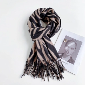 Flat lay of warm beige and black zebra striped cashmere scarf with soft tassel details